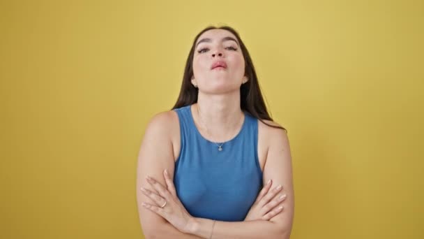 Fiatal gyönyörű spanyol nő áll a karját keresztbe tett gesztussal mond igen kézzel át izolált sárga háttér - Felvétel, videó