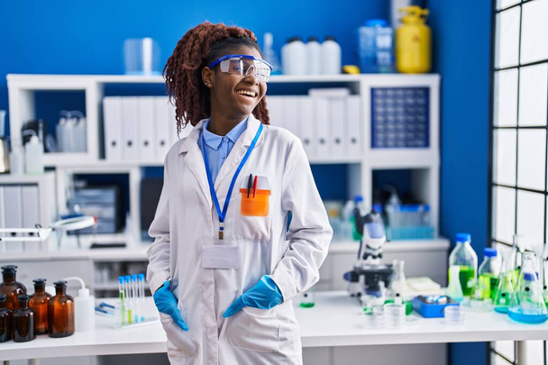 Afrikaans amerikaanse vrouw wetenschapper glimlachen zelfverzekerd staan op laboratorium - Foto, afbeelding