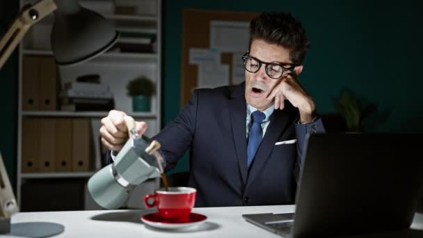 Hombre hispano joven trabajador de negocios cansado trabajando vertiendo café en la taza en la oficina - Imágenes, Vídeo
