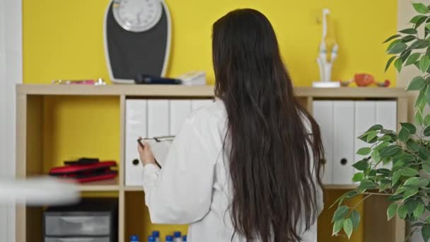 Молода красива іспаномовна жінка лікар тримає кишеню посміхаючись в клініці - Кадри, відео