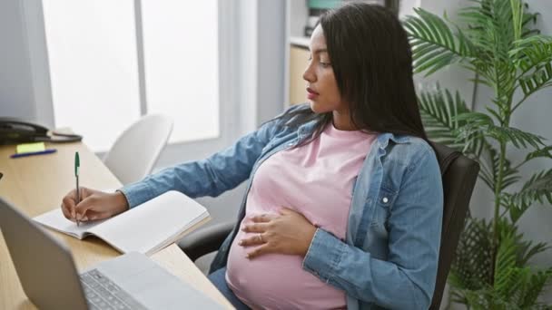 Fiatal spanyol üzletasszonyt vár, feladatzsonglőrködik a szakmájában, érzékenyen egyensúlyozza a terhességet és a munkát - jegyzetelés a laptopján egy nyugodt irodában - Felvétel, videó
