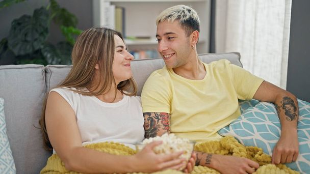 Piękna para jedząca popcorn uśmiechnięta w domu - Zdjęcie, obraz