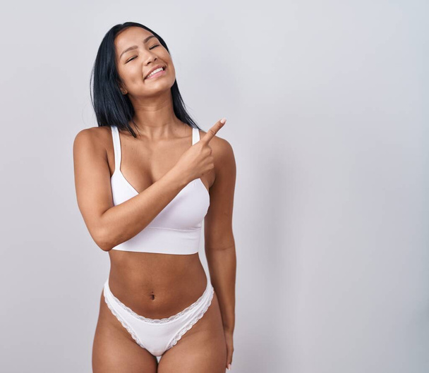 Hispanic woman wearing lingerie cheerful with a smile on face pointing with hand and finger up to the side with happy and natural expression  - Photo, Image