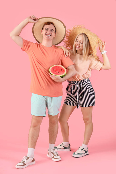 Νεαρός όμορφος άντρας και γυναίκα με μισό φρέσκο καρπούζι σε ροζ φόντο - Φωτογραφία, εικόνα