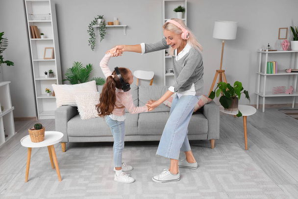 Kleines Mädchen mit Großmutter im Kopfhörer tanzt zu Hause - Foto, Bild