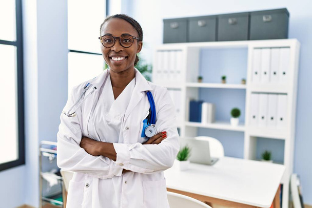 African american woman doctor smiling confident standing with arms crossed gesture at clinic - Photo, Image