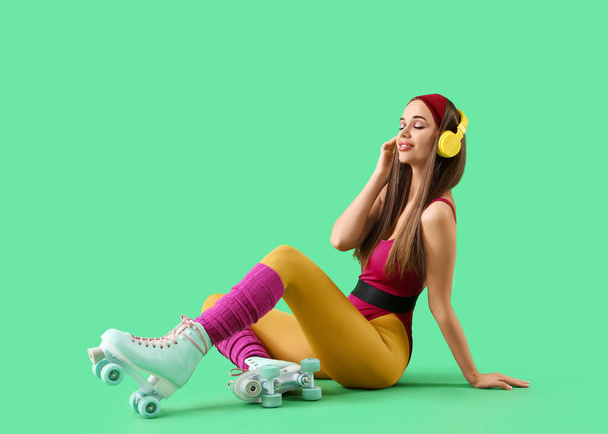 Urheilullinen nuori nainen kuulokkeissa istuu vihreällä taustalla - Valokuva, kuva