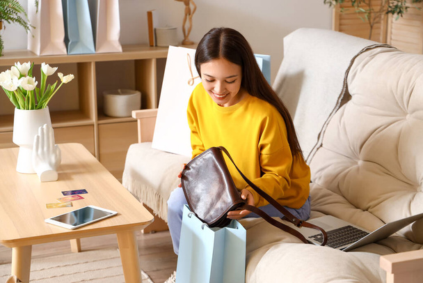 Giovane donna asiatica con nuova borsa a casa. Shopping online - Foto, immagini