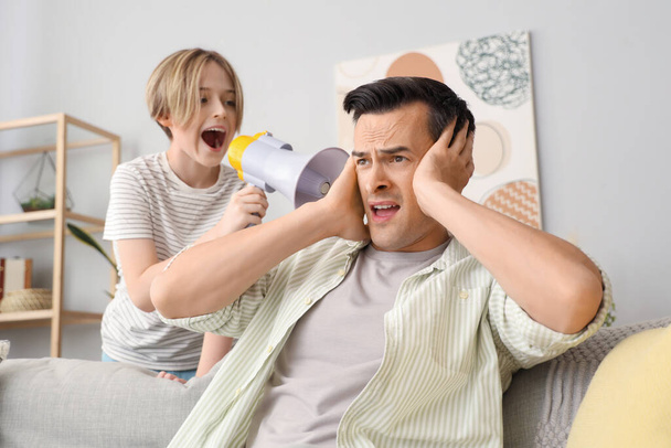 Giovane uomo stressato del suo rumoroso piccolo figlio con megafono a casa - Foto, immagini