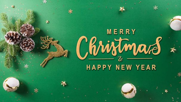 Navidad y año nuevo concepto de fondo. Vista superior de la bola de Navidad, renos, cono de pino y copo de nieve sobre fondo verde. - Foto, Imagen