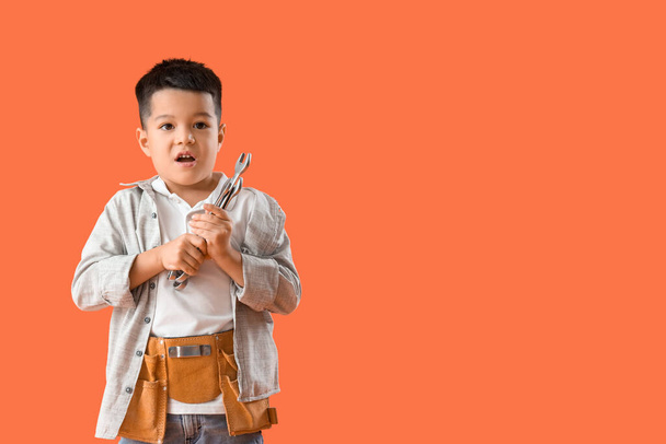 Piccolo lavoratore scioccato con chiavi su sfondo arancione - Foto, immagini