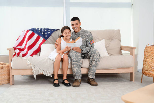 Soldaat met zijn dochtertje die thuis een boek leest. Veterans Day viering - Foto, afbeelding