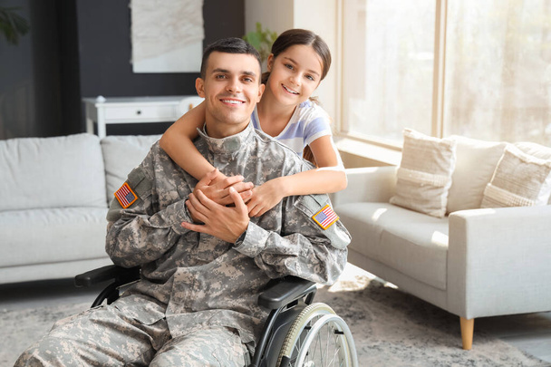 Soldier in wheelchair with his little daughter at home. Veterans Day celebration - Photo, Image