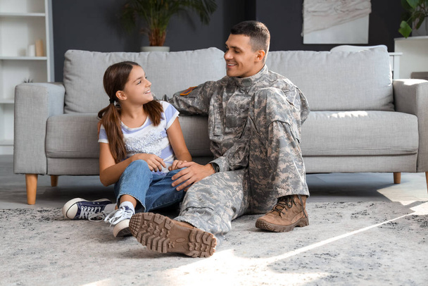 Soldat mit seiner kleinen Tochter zu Hause sitzend. Feier zum Veteranentag - Foto, Bild