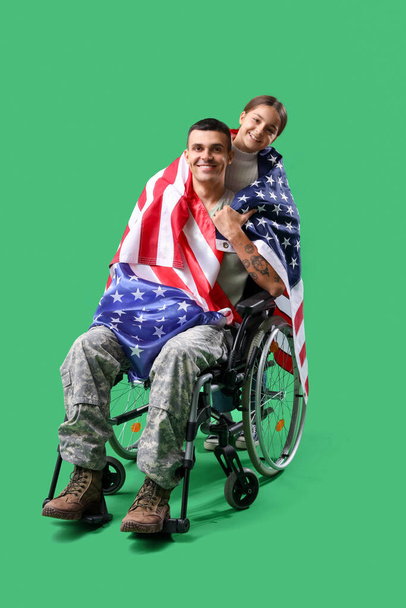 アメリカの国旗を持った車椅子の兵士と,緑色の背景にある彼の小さな娘. 退役軍人の日のお祝い - 写真・画像