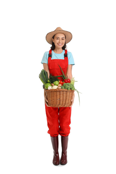 Vrouwelijke boer met mand van groenten op witte achtergrond - Foto, afbeelding