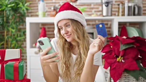 Mujer rubia joven con teléfono inteligente celebrando la Navidad en casa - Imágenes, Vídeo
