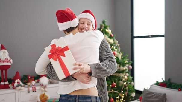 dos hombres pareja celebrando navidad celebración regalo abrazándose entre sí en casa - Foto, Imagen