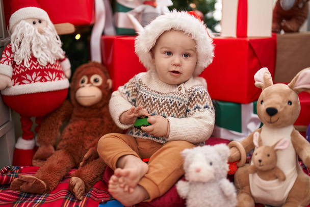 Adorabile bambino caucasico che gioca con il giocattolo dell'auto seduto sul pavimento dai regali di Natale a casa - Foto, immagini