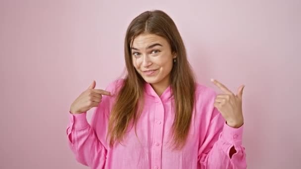 Lachende jonge Spaanse vrouw vol vertrouwen nee zeggen, wijzen naar zichzelf met de vinger, glimlachen terloops over roze geïsoleerde achtergrond - geniet van plezier, koele levensstijl expressie - Video