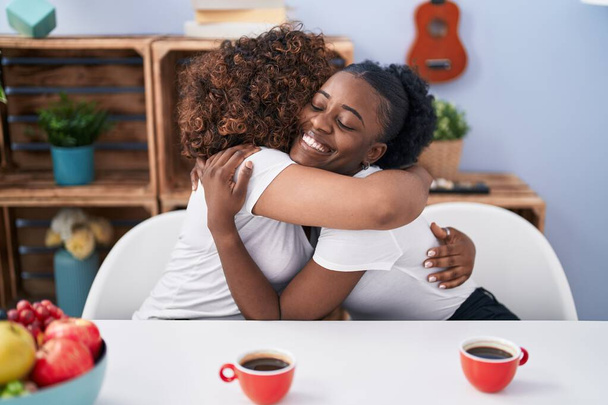 Les femmes afro-américaines mère et fille s'embrassant en buvant du café à la maison - Photo, image