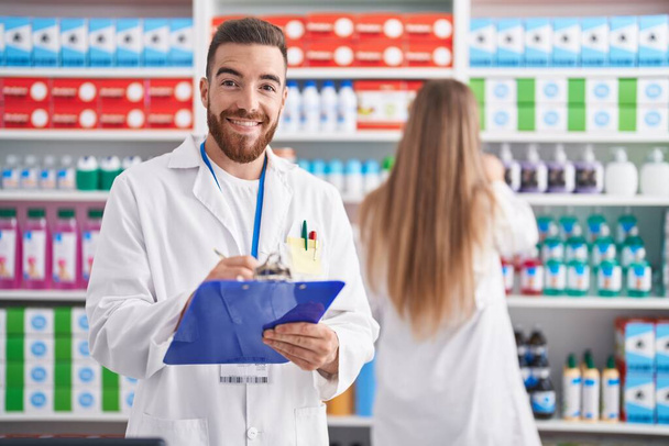 Mies ja nainen farmaseutit hymyilee luottavainen kirjallisesti asiakirjaan apteekissa - Valokuva, kuva