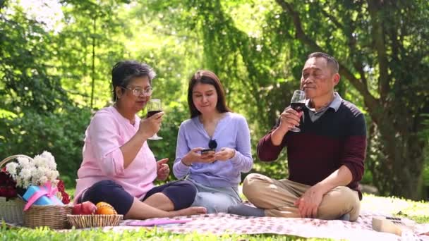 Happy asijské rodina cestování dělat činnosti piknik park starat se o jejich zdraví sedí tanec a pití červeného vína otec a matka sedět spolu zdravá dcera podpora rodinného vztahu. - Záběry, video