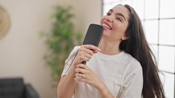 Νεαρή όμορφη ισπανίδα τραγουδίστρια με πινέλο ως μικρόφωνο στο υπνοδωμάτιο - Πλάνα, βίντεο