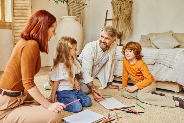 genitori allegri e bambini che si riuniscono sul pavimento in soggiorno moderno, esprimendo creatività - Foto, immagini