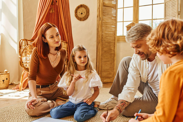 счастливый человек, приближающийся к счастливой семье, сидя на полу в уютной гостиной, занимаясь творчеством - Фото, изображение