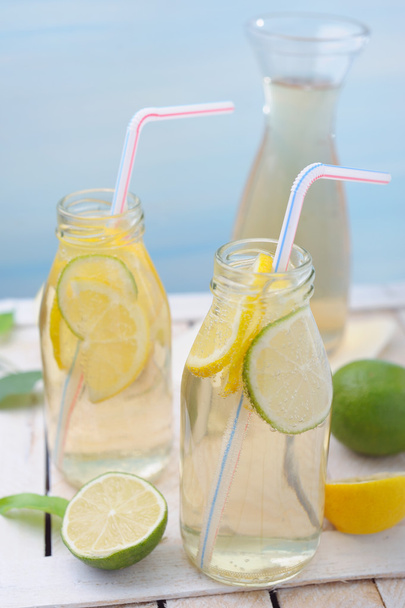 Jarra y vasos con limonada y limones y lima sobre mesa rústica
 - Foto, imagen