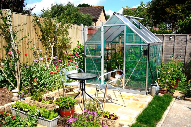 New modern polycarbonate hybrid greenhouse with a table and chairs in the foreground, Chard, Somerset, UK, Europe - Photo, Image