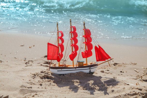 Πλοίο με κόκκινα πανιά σε φόντο παραλίας. Σχέδιο ταξιδιού, διακοπών και κρουαζιέρας - Φωτογραφία, εικόνα