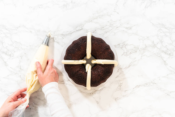 Plat gelegd. Met precisie wordt de Chocolate Bundt Cake voorzichtig uit de pan gehaald - versierd met heerlijke roomkaas glazuur, waardoor een heerlijke traktatie ontstaat die zeker zal verrukken. - Foto, afbeelding