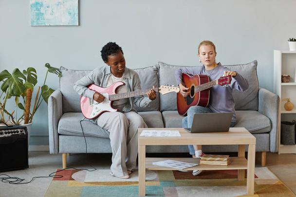 Minimaalinen täyspitkä muotokuva kaksi nuorta naista soittaa kitaraa yhdessä studiossa ja säveltää musiikkia, kopioi tilaa - Valokuva, kuva