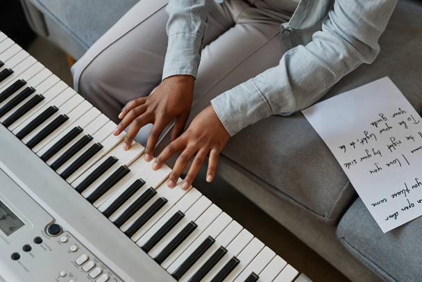 Vista superior de cerca de la joven mujer presionando teclas de piano mientras compone música en casa con letras de canciones, espacio de copia - Foto, imagen