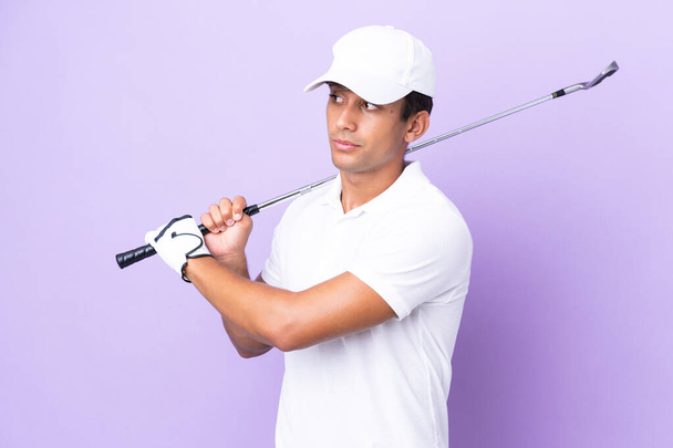 Jovem caucasiano isolado no fundo roxo jogando golfe - Foto, Imagem