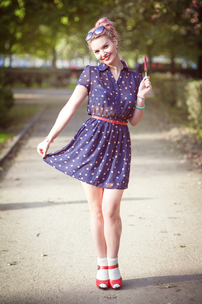 Beautiful young woman in fifties style with braces holding candy - Photo, Image