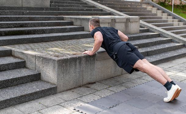 Incline push-up doing by a young athletic man. Push-up modification for beginners - Photo, Image