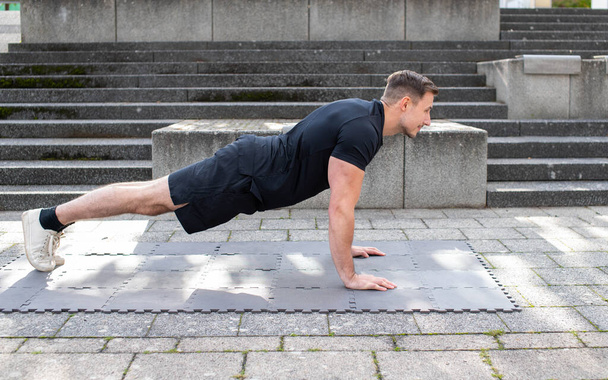 Young man in push-up position on concrete background. - Photo, Image