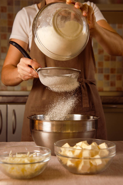 woman hands sifts flour through sieve. saturate flour with air for tender texture of dough - Photo, Image