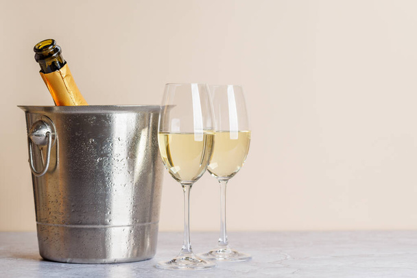 Dvě sklenice šampaňského a láhev v kbelíku s ledem. Vánoční přání šablona s kopírovacím prostorem - Fotografie, Obrázek