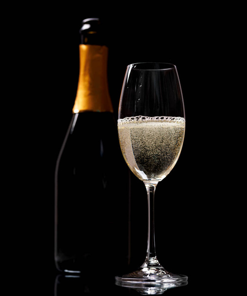 Sklo šampaňské a láhev na černém pozadí - Fotografie, Obrázek