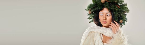 winter beauty, attractive woman with natural pine wreath posing in white clothes on grey, banner - Photo, Image
