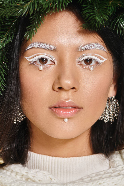 winter beauty, close up of attractive woman with white eye makeup and beads on face posing in wreath - Foto, Imagem