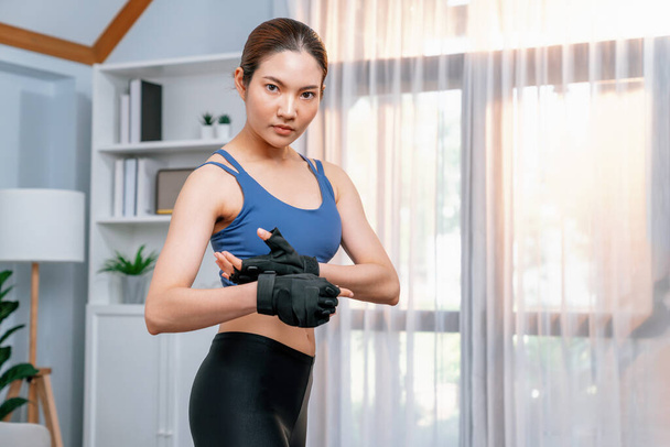 Fit young asian woman portrait in sportswear preparing herself before healthy exercising routine at home. Domestic fitness workout training on living room. Vigorous - Photo, Image