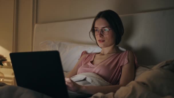 Fröhliche Frau blättert Laptop zu Hause Nacht Nahaufnahme. Lächelndes Mädchen, das vor dem Schlafen Nachrichten im Internet eintippt. Freiberufler arbeitet Computer-Spätfertigungsprojekt. Glückliche weibliche Abkühlung am Wochenende. - Filmmaterial, Video
