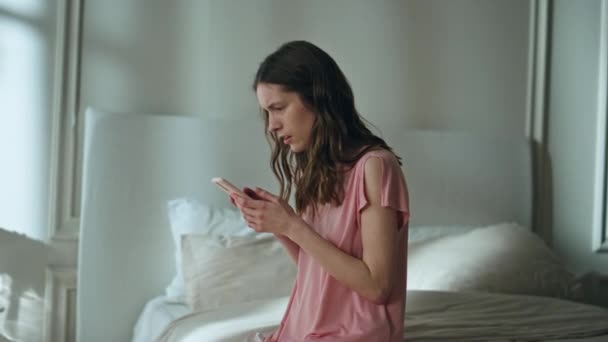Woman reading sad news at night. Frustrated girl checking mobile phone messages receive shocking sms. Stressed female sitting bed looking smartphone in dark room. Relationship breakup problems concept - Footage, Video