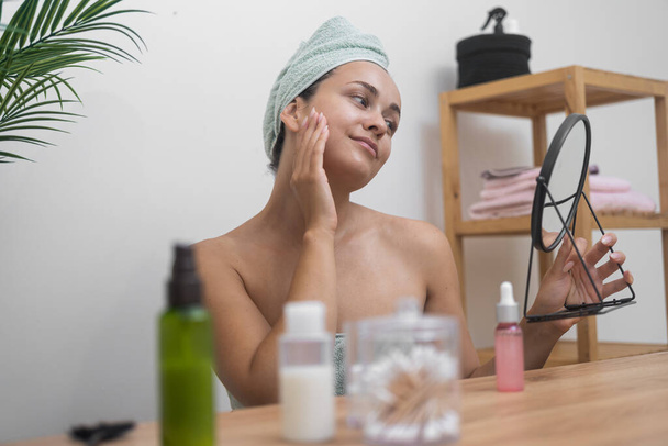 Miroir d'allure : Une dame, à sa coiffeuse, admire sa peau veloutée tout en se livrant à des soins cosmétiques.  - Photo, image