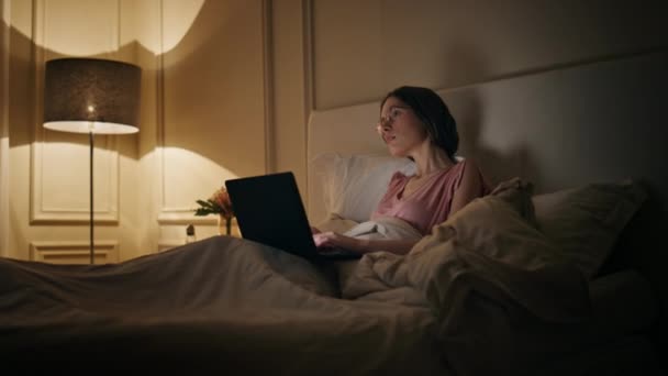 Refroidir femme parcourant ordinateur portable la nuit. Joyeux pigiste travaillant tard dans le lit dactylographiant l'ordinateur. Focalisé étudiant gestionnaire étude écran de recherche. Femme détendue riant bavarder amis en ligne le soir - Séquence, vidéo